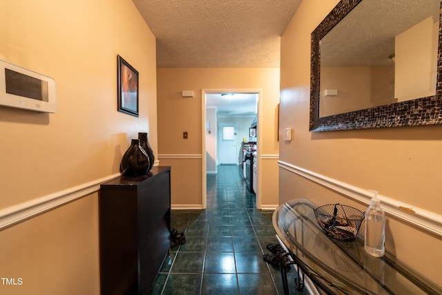 hall with a textured ceiling and dark tile patterned floors