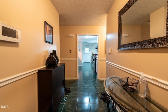 hall with dark tile patterned flooring and a textured ceiling