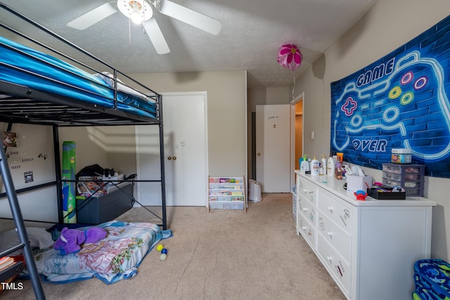 carpeted bedroom featuring ceiling fan and a textured ceiling