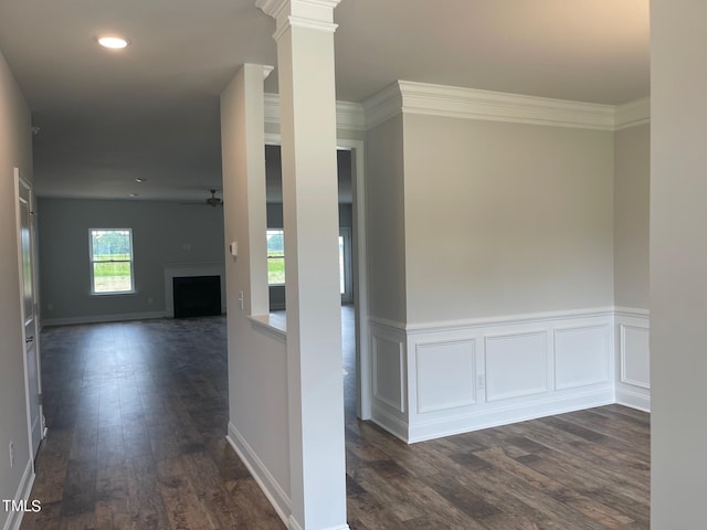 hallway with decorative columns, crown molding, and dark wood-type flooring