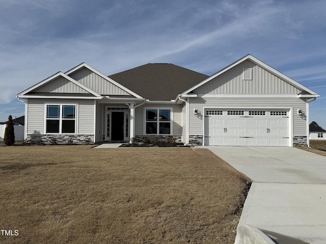 craftsman house with stone siding, a front lawn, an attached garage, and driveway