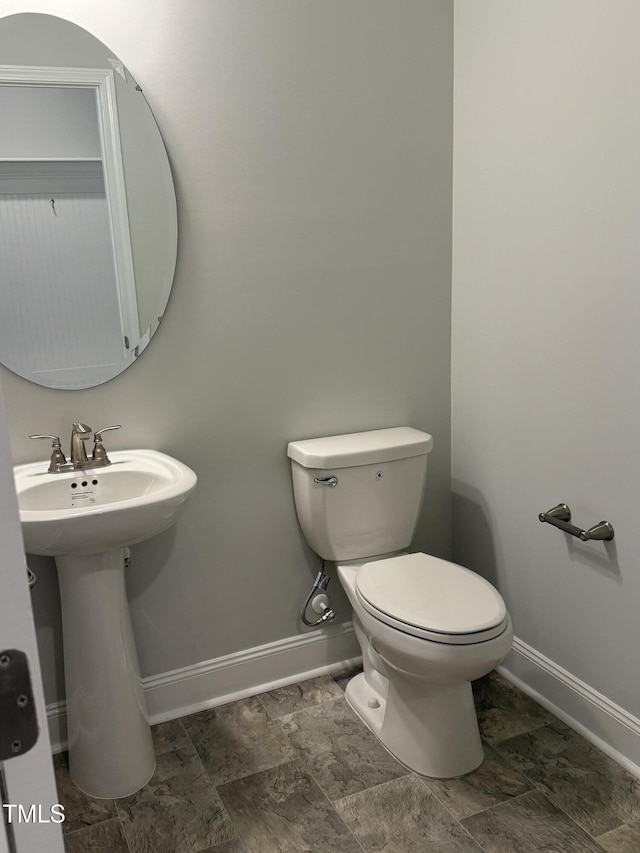 half bath with a sink, toilet, and baseboards