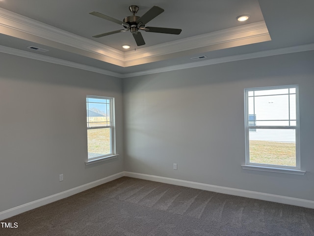 spare room featuring visible vents, baseboards, dark carpet, a raised ceiling, and crown molding