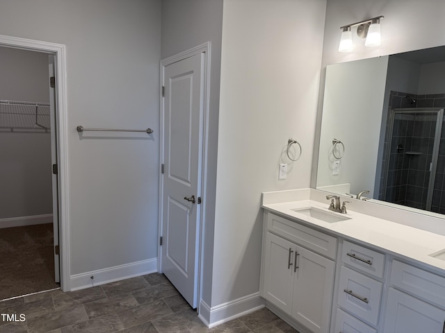 bathroom featuring baseboards, a walk in closet, tiled shower, and vanity