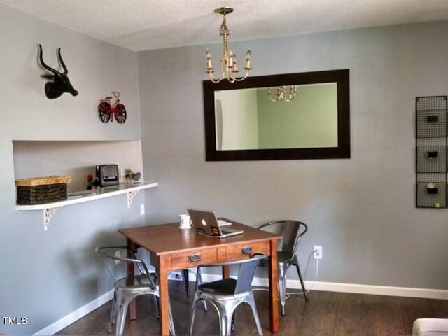 dining area with hardwood / wood-style floors, a textured ceiling, and an inviting chandelier