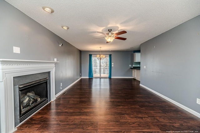 unfurnished living room featuring ceiling fan with notable chandelier, dark hardwood / wood-style floors, and a textured ceiling