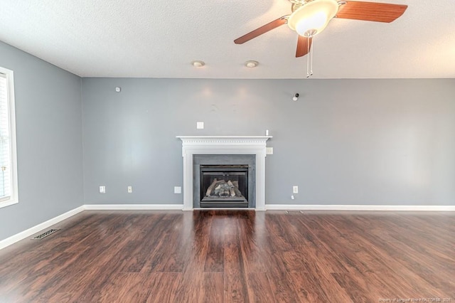 unfurnished living room with ceiling fan, dark hardwood / wood-style flooring, and a textured ceiling