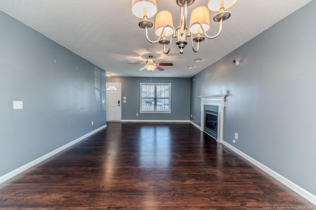 unfurnished living room featuring a textured ceiling, ceiling fan with notable chandelier, and dark wood-type flooring