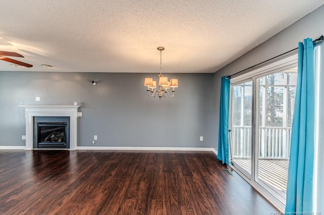 unfurnished living room with a textured ceiling, ceiling fan with notable chandelier, and dark wood-type flooring