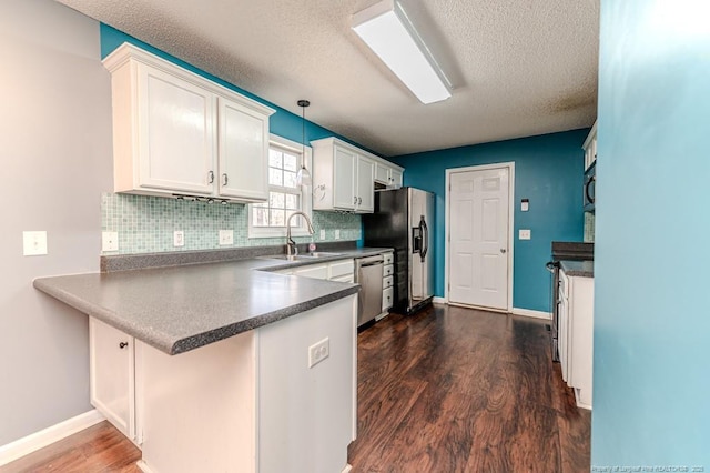 kitchen with stainless steel appliances, kitchen peninsula, pendant lighting, decorative backsplash, and white cabinets