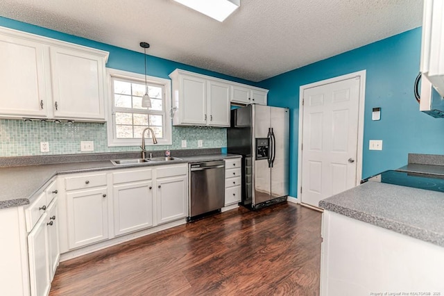 kitchen with pendant lighting, white cabinets, sink, a textured ceiling, and stainless steel appliances