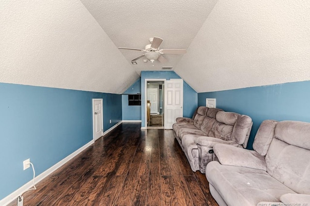 living room with a textured ceiling, vaulted ceiling, ceiling fan, and dark wood-type flooring