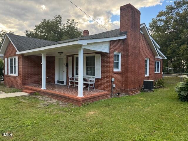 rear view of house with a porch and a yard