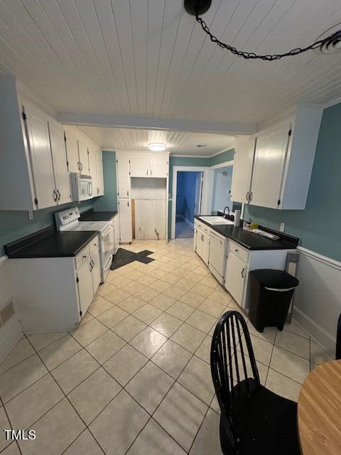 kitchen with white appliances, white cabinets, sink, light tile patterned floors, and beamed ceiling