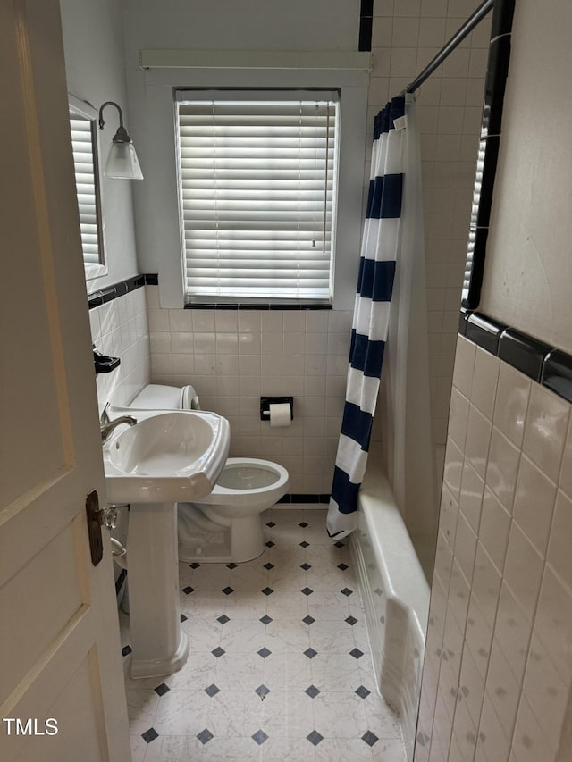 bathroom with shower / bath combo, toilet, and tile walls