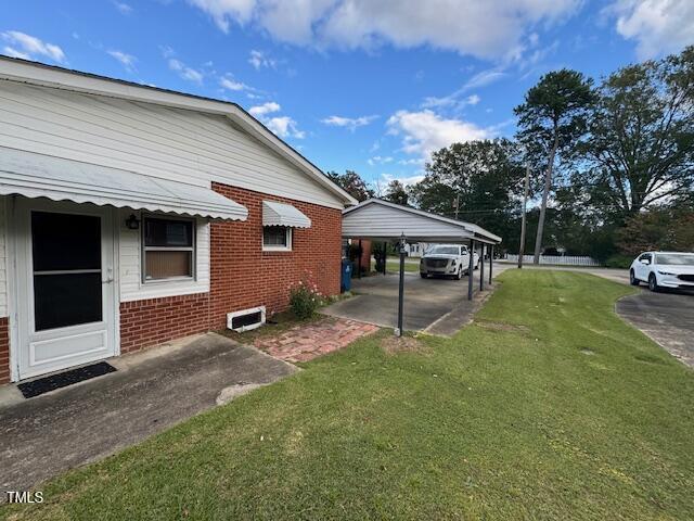 view of side of home featuring a yard and a carport