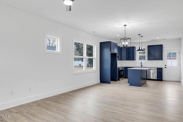 kitchen with appliances with stainless steel finishes, a wealth of natural light, blue cabinets, decorative light fixtures, and a center island