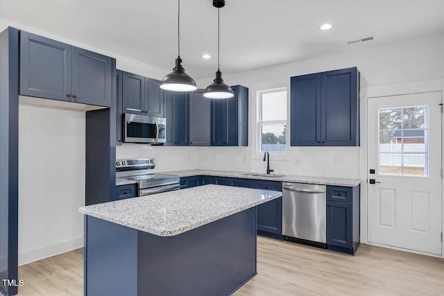 kitchen with blue cabinets, sink, appliances with stainless steel finishes, decorative light fixtures, and a kitchen island