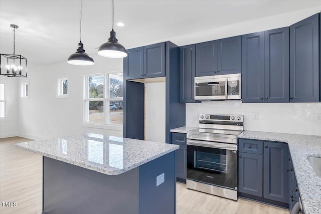 kitchen featuring blue cabinetry, light stone counters, hanging light fixtures, and appliances with stainless steel finishes