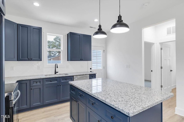 kitchen featuring appliances with stainless steel finishes, sink, blue cabinetry, pendant lighting, and a center island