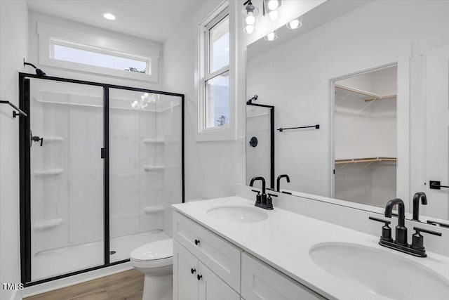 bathroom with a shower with shower door, toilet, wood-type flooring, and vanity