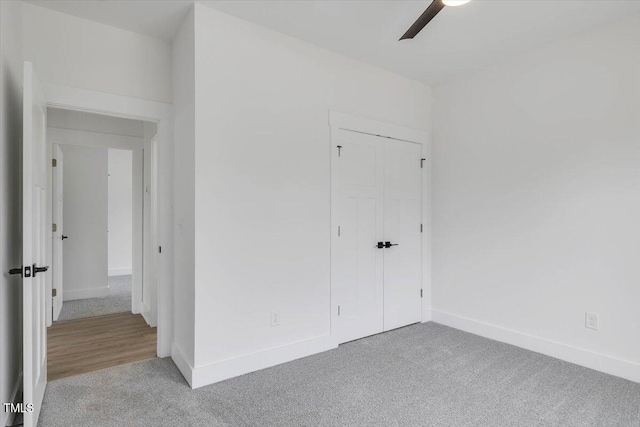 unfurnished bedroom with ceiling fan, a closet, and light colored carpet