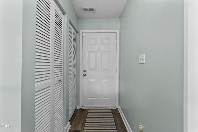 hallway with dark hardwood / wood-style floors and a textured ceiling