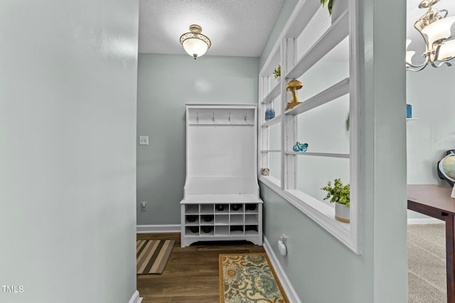 mudroom featuring dark wood-type flooring, an inviting chandelier, and a textured ceiling