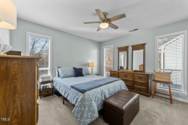 bedroom featuring light carpet, a textured ceiling, and ceiling fan