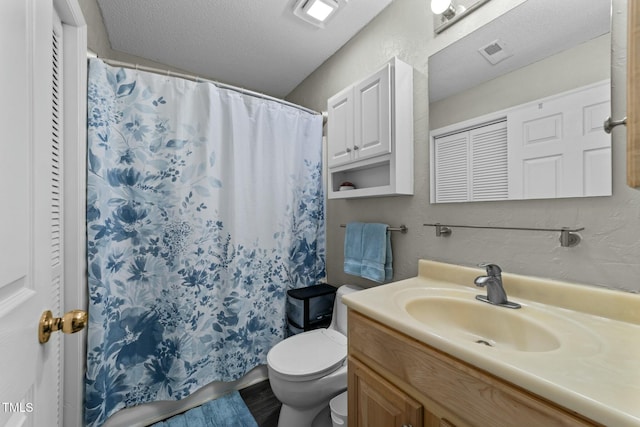 bathroom with vanity, curtained shower, a textured ceiling, and toilet