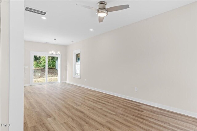 empty room featuring ceiling fan with notable chandelier and light hardwood / wood-style floors
