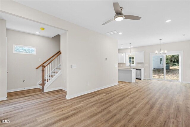 unfurnished living room with ceiling fan with notable chandelier, sink, and light hardwood / wood-style flooring