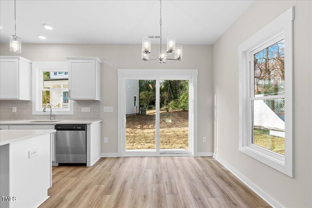 kitchen with sink, stainless steel dishwasher, tasteful backsplash, decorative light fixtures, and white cabinetry