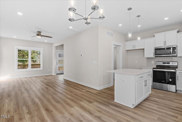 kitchen featuring white cabinetry, hanging light fixtures, a kitchen island, and stainless steel appliances