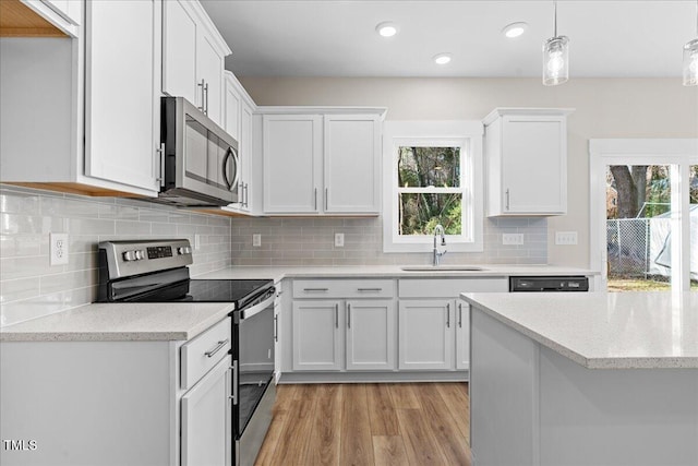 kitchen with white cabinets, decorative light fixtures, stainless steel appliances, and sink