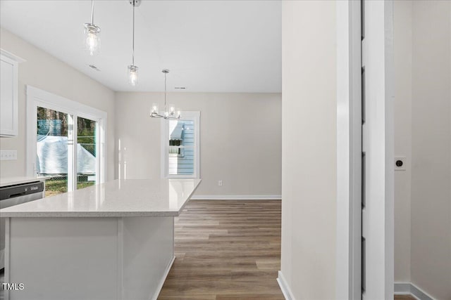 kitchen featuring white cabinetry, hanging light fixtures, stainless steel dishwasher, a chandelier, and hardwood / wood-style flooring