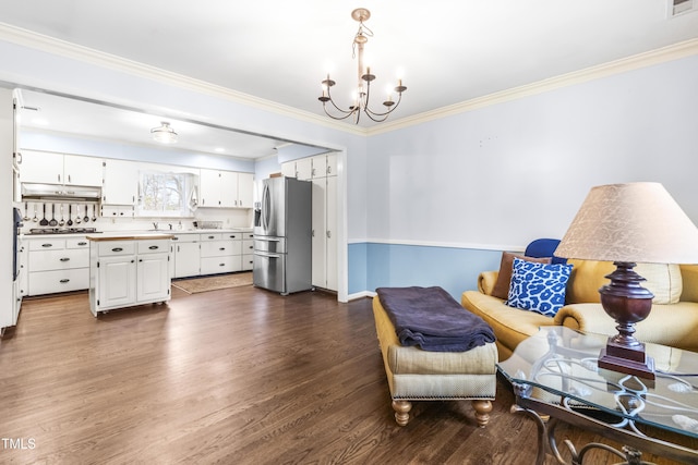 living area featuring ornamental molding, dark hardwood / wood-style floors, and a chandelier