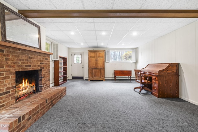 living area featuring a baseboard radiator, carpet, a brick fireplace, and a drop ceiling