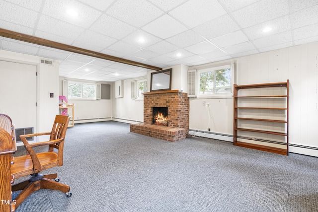 office space with a baseboard heating unit, carpet floors, a paneled ceiling, and a fireplace