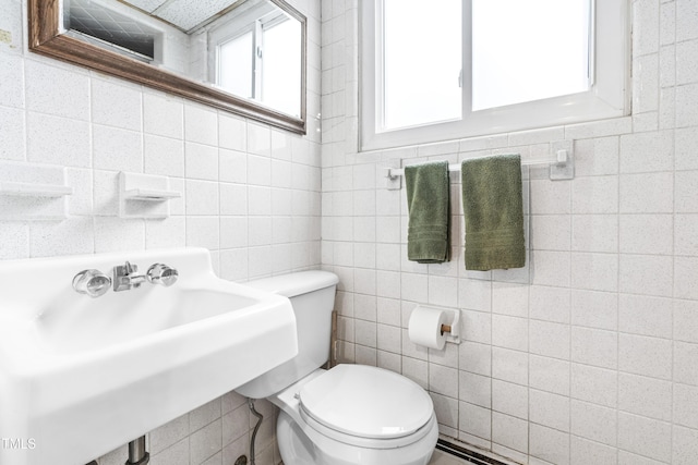 bathroom with tile walls, sink, and toilet