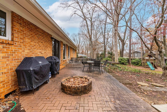 view of patio featuring area for grilling, an outdoor fire pit, and a playground