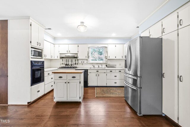 5205 Rembert Dr, Raleigh, NC 27612 - kitchen featuring stainless steel appliances, under cabinet range hood, a sink, white cabinets, and dark wood finished floors