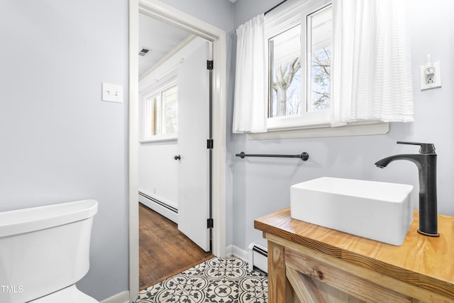 5205 Rembert Dr, Raleigh, NC 27612 - bathroom featuring baseboard heating, toilet, baseboards, and vanity