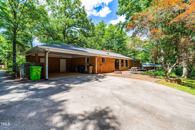 5205 Rembert Dr, Raleigh, NC 27612 - view of front facade featuring driveway, brick siding, and a carport