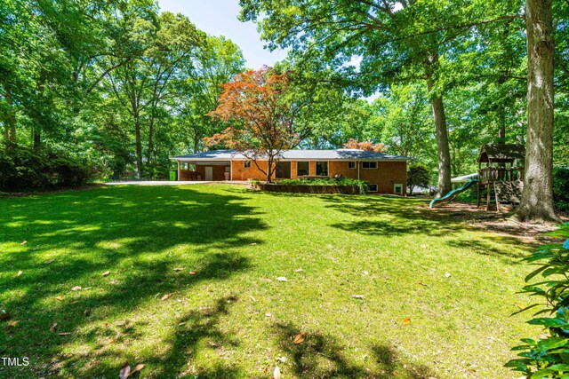 5205 Rembert Dr, Raleigh, NC 27612 - view of grassy yard featuring a playground, a carport, and driveway