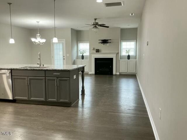 kitchen featuring sink, gray cabinetry, a kitchen island with sink, decorative light fixtures, and stainless steel dishwasher