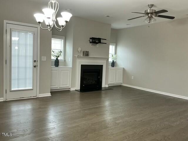 unfurnished living room featuring dark wood-type flooring and ceiling fan with notable chandelier