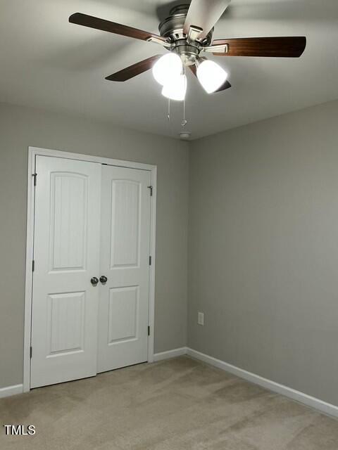 unfurnished bedroom with light colored carpet, a closet, and ceiling fan