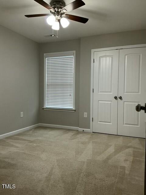 unfurnished bedroom with light carpet, a closet, and ceiling fan