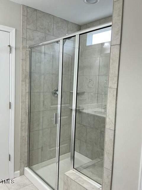 bathroom with an enclosed shower and tile patterned flooring